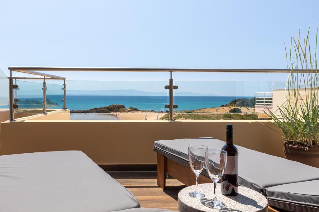Terases skats uz pludmali, kur uz galda ir vīna pudele un glāzes, radot relaksējošu atmosfēru. Ideāla vieta mierīgai atpūtai un izbaudīšanai.