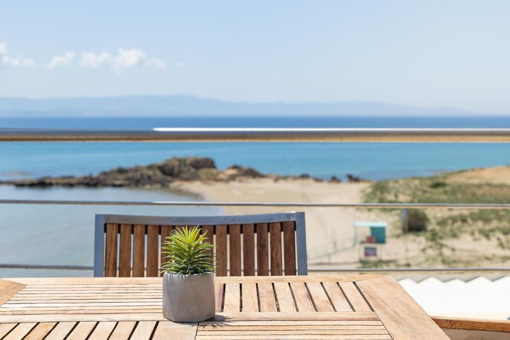 Jūras krasta skats no terases ar koka galdu un augiem podiņā. Svaiga gaisa un saules gaismas atmosfēra.