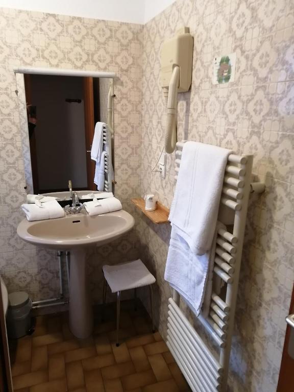 Mazo vannas istabu ar baltām dvielēm, galda spoguli un siltā ūdens radiatoru, kā arī nelielu krēslu un fēnu.