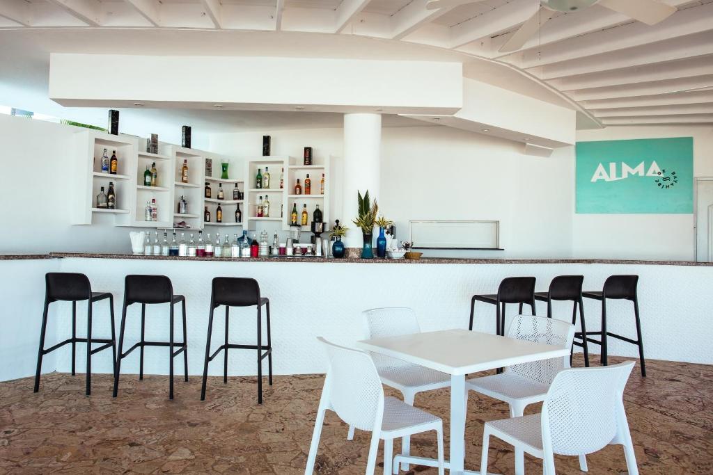 Mūsdienīgs bārs ar elegantu interjeru, kurā redzama plaša dzērienu izvēle un stilīgas sēdvietas. Uz sienas ir redzams bāra nosaukums "ALMA".