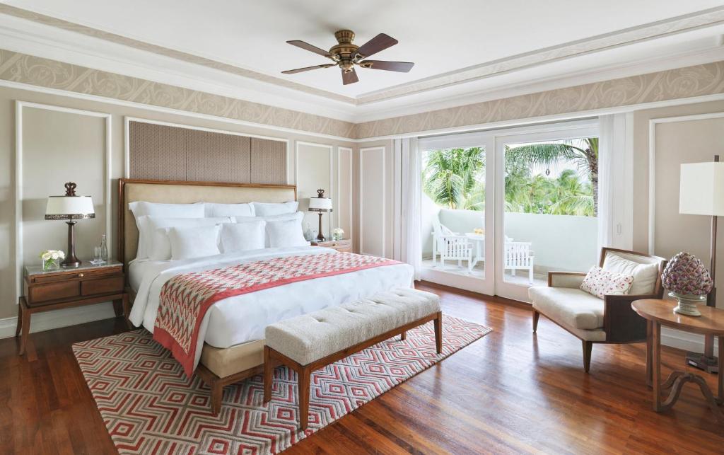 Mūsdienīgs guļamistabas interjers ar plašu gultu, elegantiem mēbeļu elementiem un lieliem logiem, kas sniedz skatu uz dārzu. 