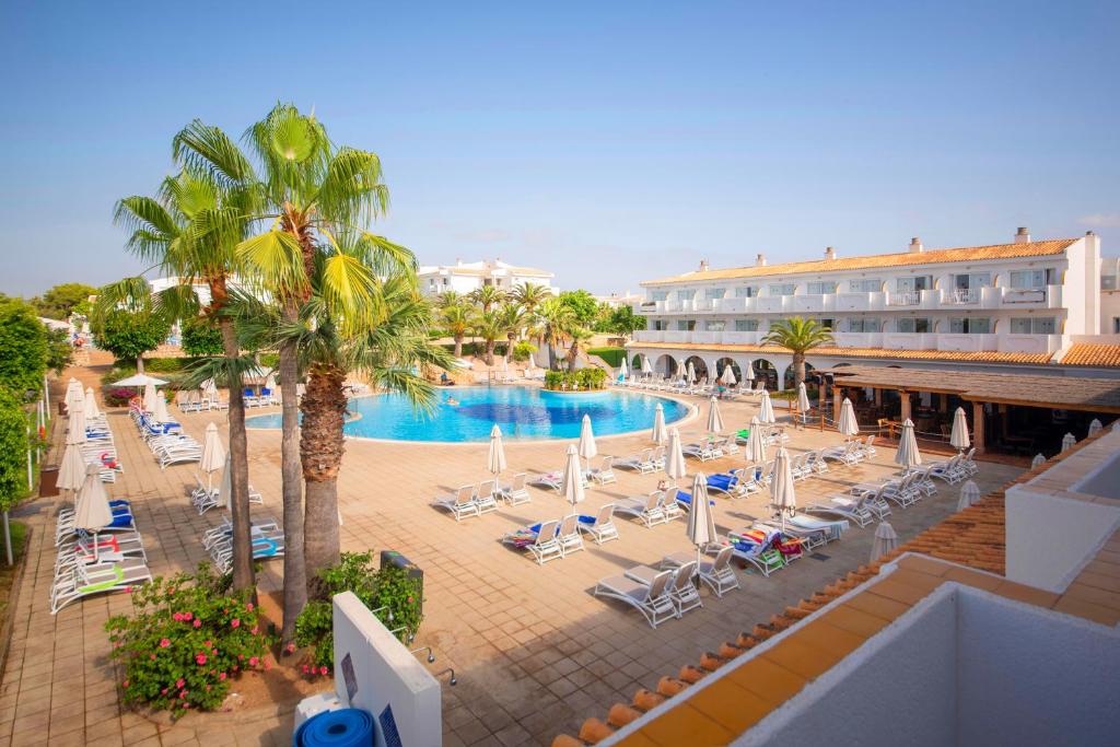 Viesnīca ar plašu baseina zonu, apjozta ar palmām un saules krēslu rindām, kas aicina uz relaksāciju. Apkārt esošās zaļās platības un skaidrā debess rada brīvdienu atmosfēru.