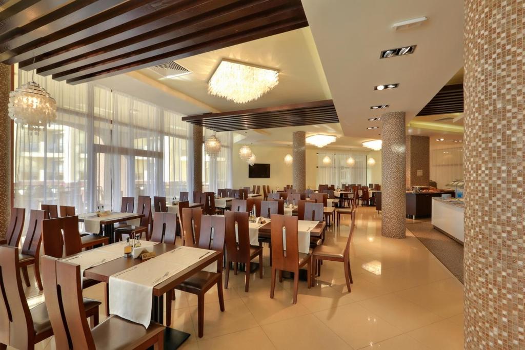 Mūsdienīgs restorāns ar elegantu interjeru, koka griestiem un plašām, gaišām telpām, kas piedāvā komfortablu ēdināšanu. Galdi ir klāti ar baltām galdautām un dekorācijām, radot patīkamu atmosfēru.