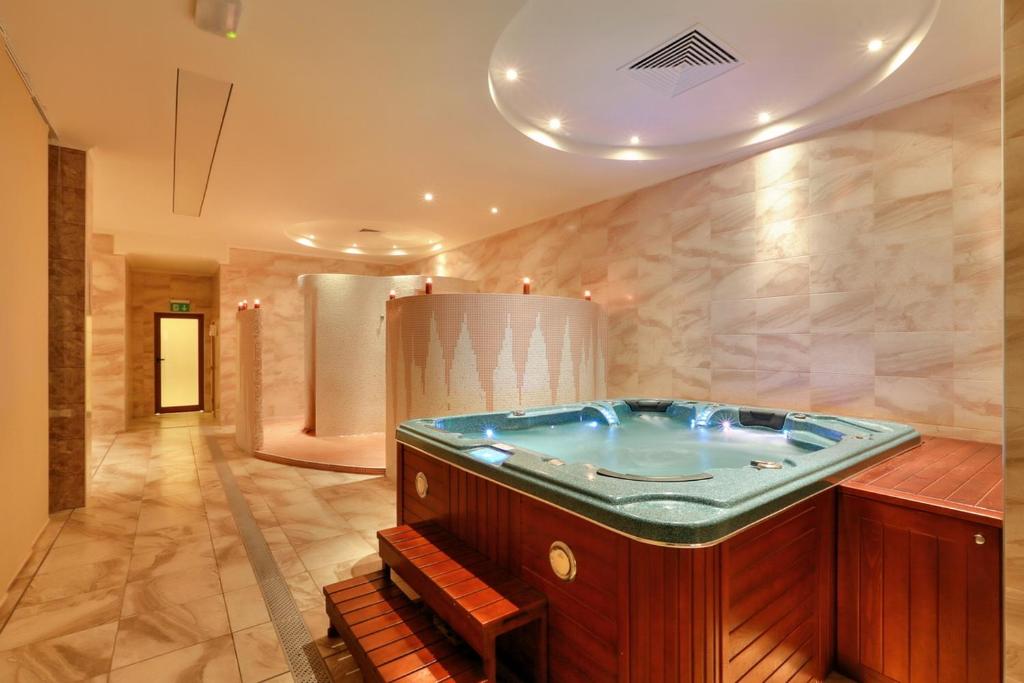 Spa telpa ar džakuzi un dušām, apgaismota ar siltu gaismu, radot relaksējošu atmosfēru. Ideāla vieta atpūtai un labsajūtai.