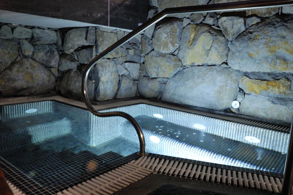 Mūsdienīgs spa baseins ar akmens sienu un izgaismotām pakāpēm, radot relaksējošu atmosfēru. Ideāls vieta atpūtai un labsajūtai.