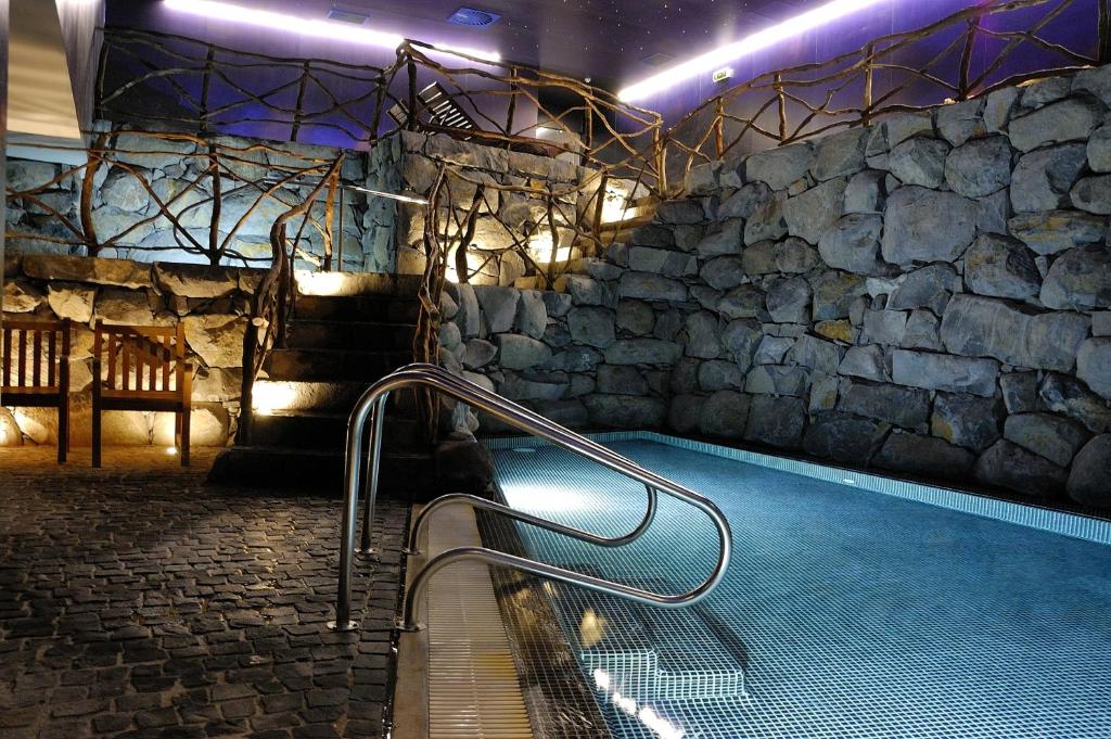 Relaksējošs spa ar akmens sienām un baseinu, kurā ir moderns apgaismojums un koka elementi. Ideāla vieta atpūtai un relaksācijai.