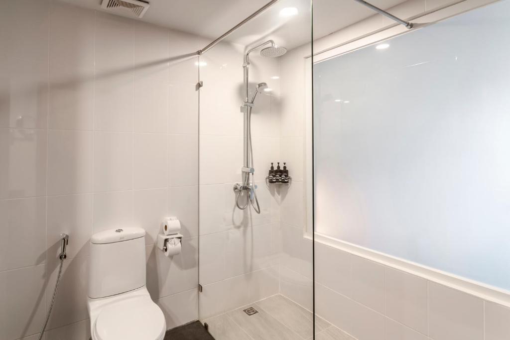 Mūsdienīga vannas istaba ar stikla dušu, tualeti un higiēnas piederumiem. Gaišas flīzes un minimālisma dizains rada svaigu un tīru atmosfēru.