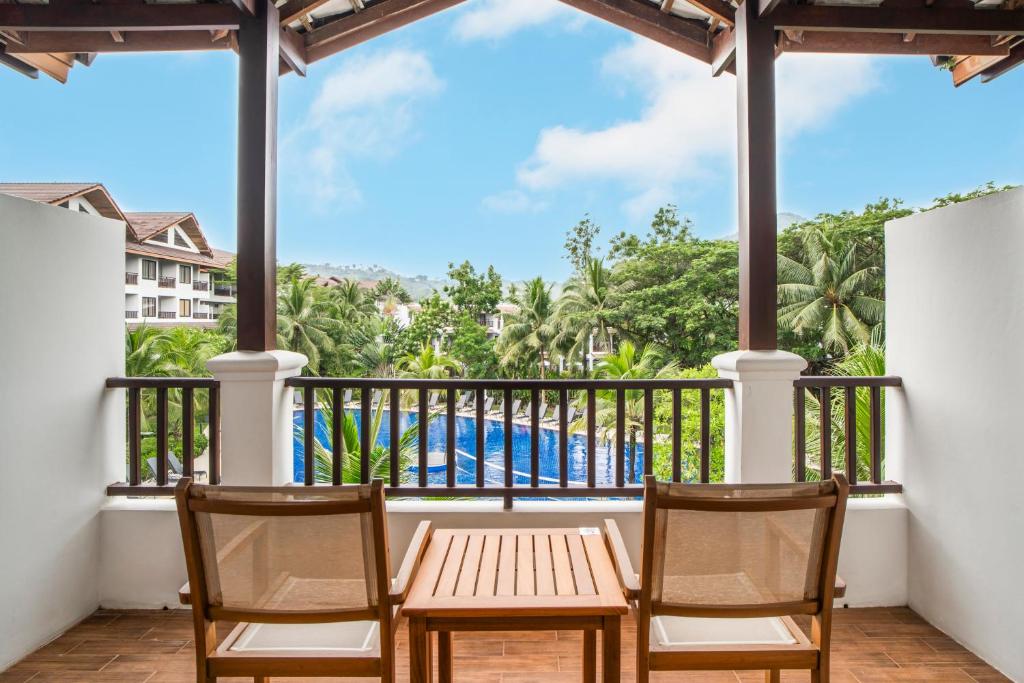 Balkons ar divām krēsliem un galdu, kas piedāvā skatu uz baseinu un zaļo dārzu. Ideāla vieta atpūtai un relaksācijai.