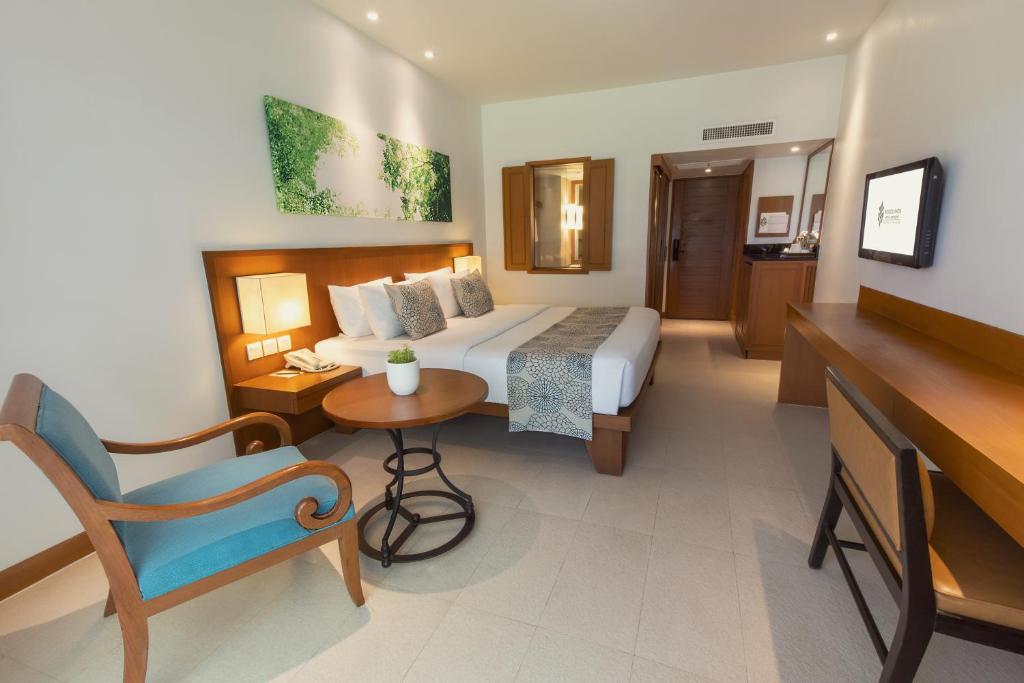 Mūsdienīga viesnīcas istaba ar dubultgultu, dīvānu, koka mēbelēm un dabas motīviem uz sienas. Istaba ir gaiša un plaša, ar ērtu dīvānu un televizoru.