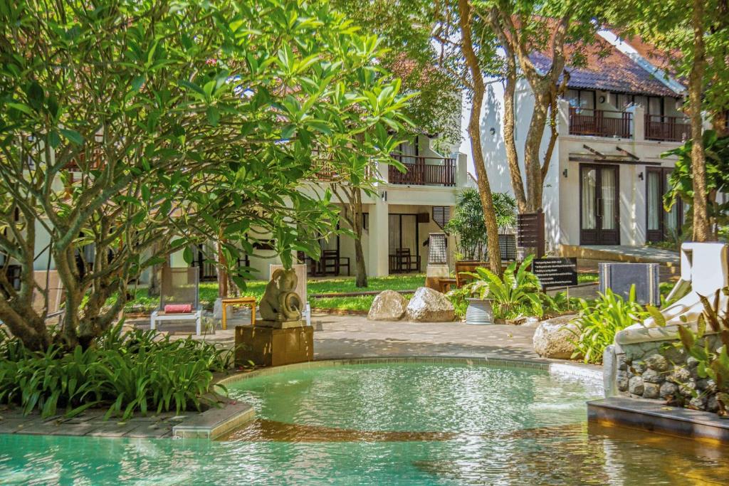 Tropu dārza ainava ar baseinu, apkārt apzaļumotām ēkām un sulīgiem kokiem, nodrošina relaksējošu atmosfēru. Ideāla vieta atpūtai un harmonijai.