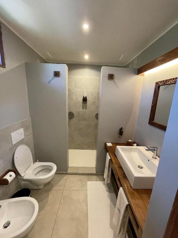 Mūsdienīgs un elegants vannas istabas interjers ar dušas kabīni, izlietni un WC. Neitrālas krāsas un dabīgā koka akcenti rada patīkamu atmosfēru.