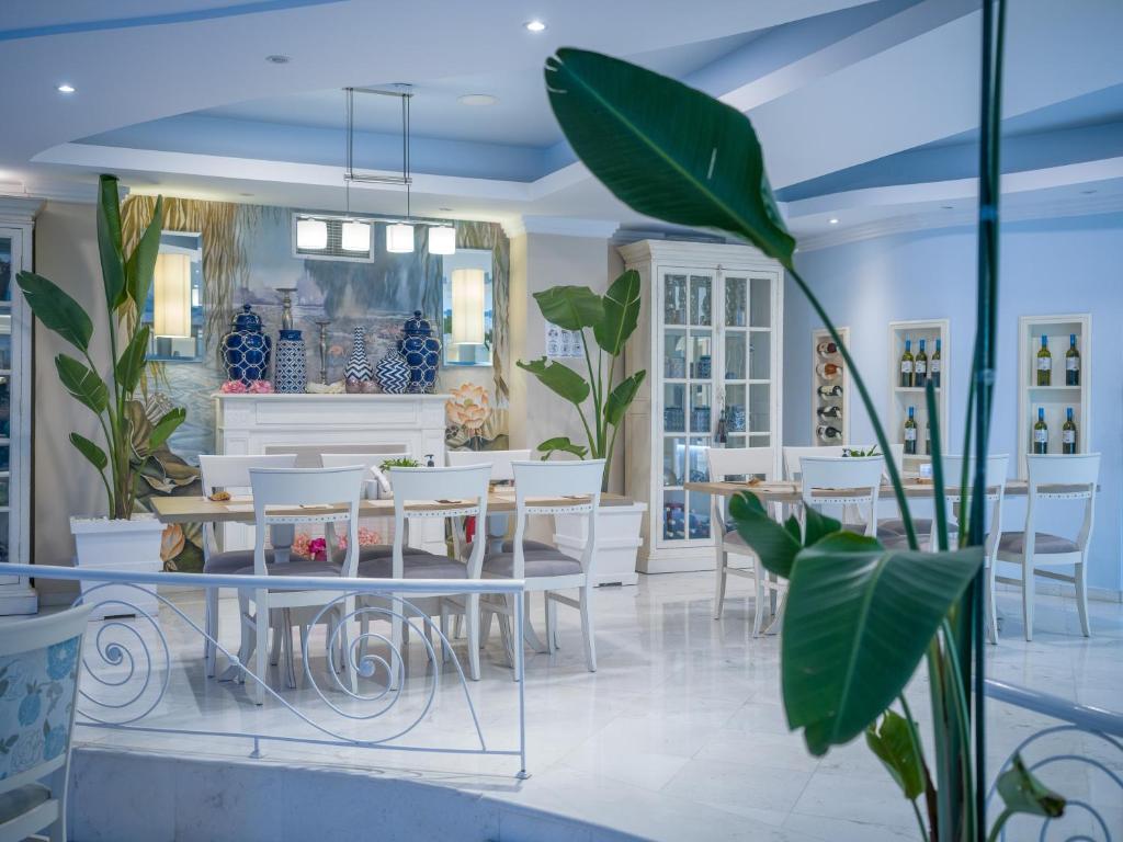 Mūsdienīgs interjers ar baltām mēbelēm un zaļām augu kompozīcijām, radot relaksējošu atmosfēru. Gaismas elementi un dekoratīvi trauki piešķir telpai elegantu izskatu.