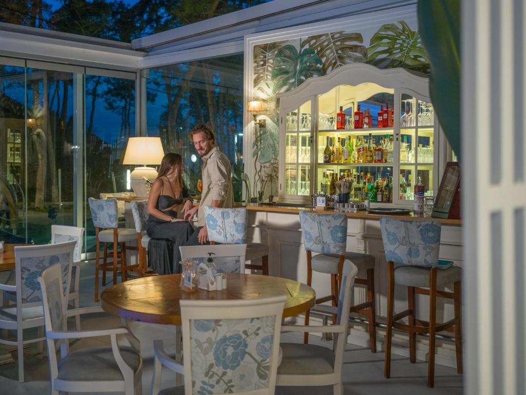 Elegants bārs ar romantisku atmosfēru, kur pāris bauda vakaru. Fons ar stikla sienām un plašu dzērienu izvēli.