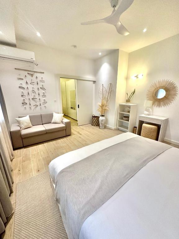 Mūsdienīgs guļamistabas interjers ar gultu, dīvānu un dekoratīviem elementiem. Telpa ir gaiša un eleganta, radot patīkamu atmosfēru.