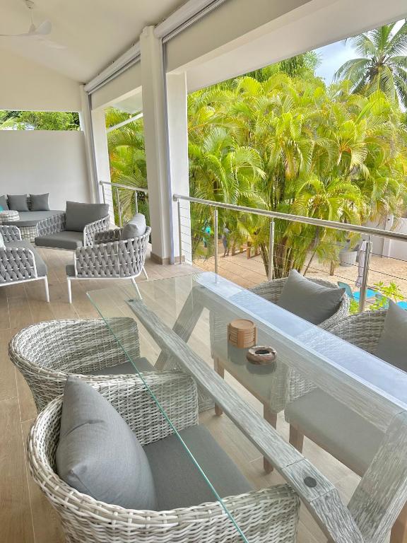 Mūsdienīga terases zona ar baltiem, vītņotiem krēsliem un stikla galdu, kas piedāvā skatu uz zaļām palmām. Ideāli piemērota relaksācijai un atpūtai.