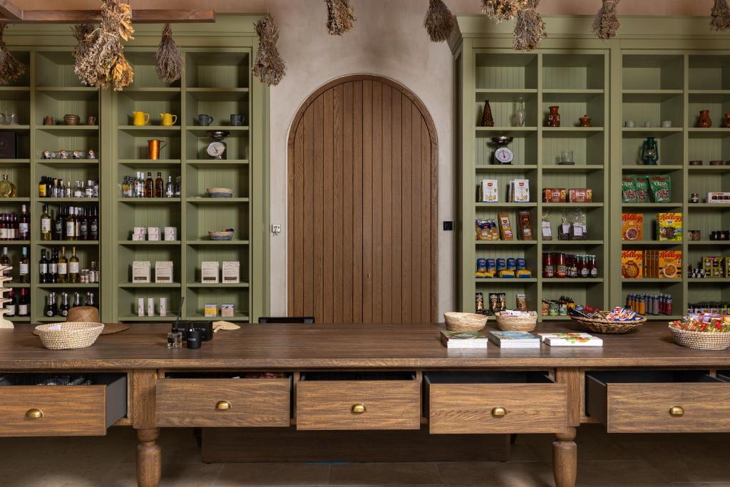 Mūsdienīga, gaumīga veikala interjers ar koka galdu, zaļām plauktiem, kuros izvietoti dažādi produkti, un dekoratīvām žāvētām garšvielām.