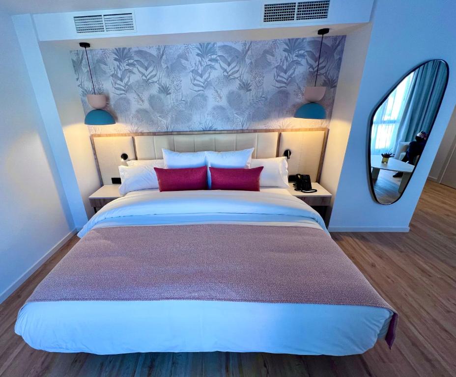 Mūsdienīgs viesnīcas numurs ar elegantu gultu un stilīgu apgaismojumu, papildināts ar augu motīvu tapetēm un modernu spoguli. Ideāla vieta atpūtai un relaksācijai.