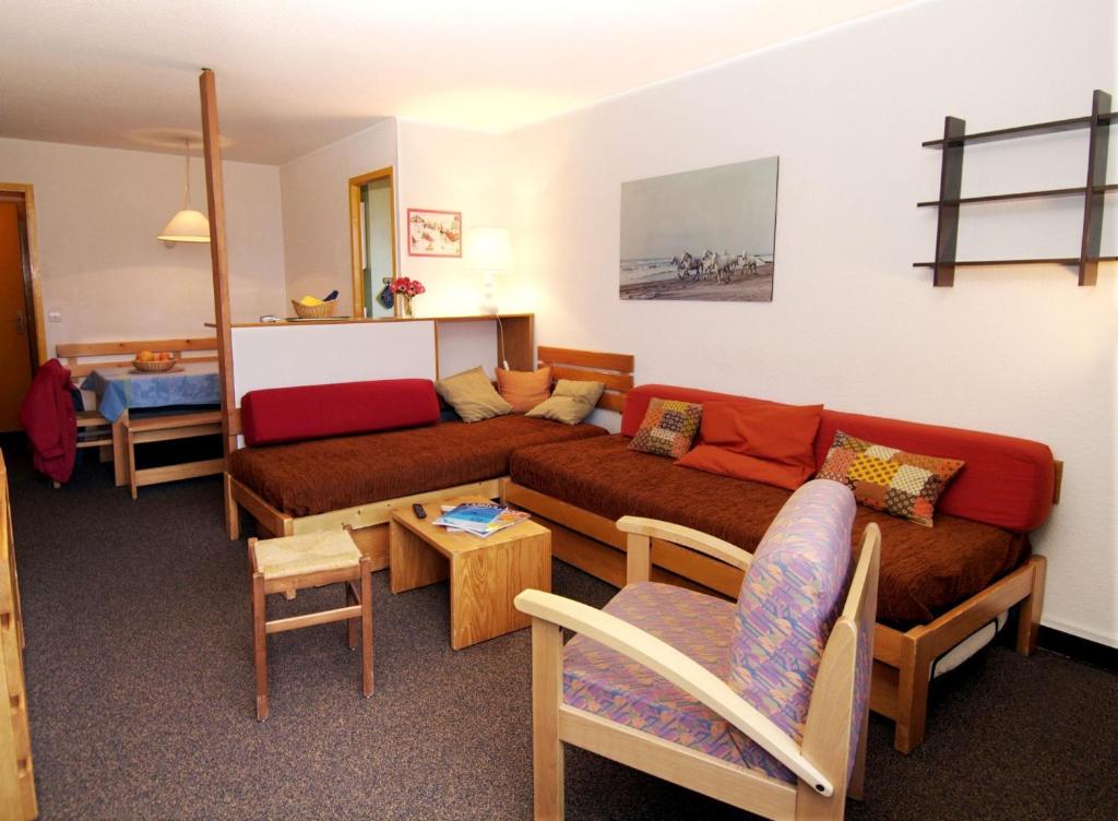 Gaiša un mājīga viesistaba ar sarkaniem dīvāniem, koka mēbelēm un mākslas darbu pie sienas. Telpa ir ērti iekārtota, radot patīkamu atmosfēru atpūtai.