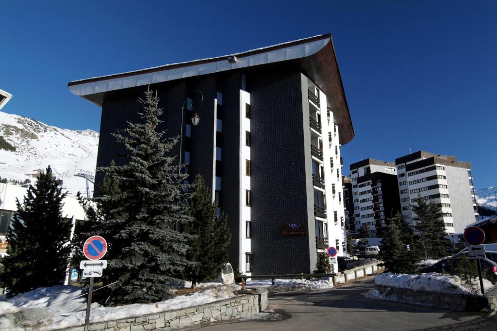 Mūsdienīga viesnīca kalnu apvidū ar sniegotiem pakalniem fonā un skujkokiem priekšplānā. Ideāla vieta ziemas sporta cienītājiem.