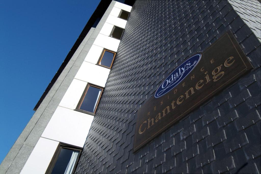 Odalys residence Chanteneige ēkas fasāde ar modernu arhitektūru un skaidru zilu debesi fonā.