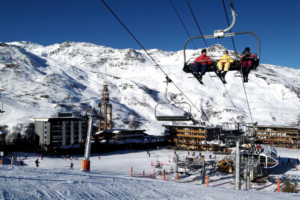 Ziemas kūrorts ar sniegotām kalnu virsotnēm un slēpotājiem, kas izmanto pacēlājus. Skats uz viesnīcām un slēpošanas trasi.