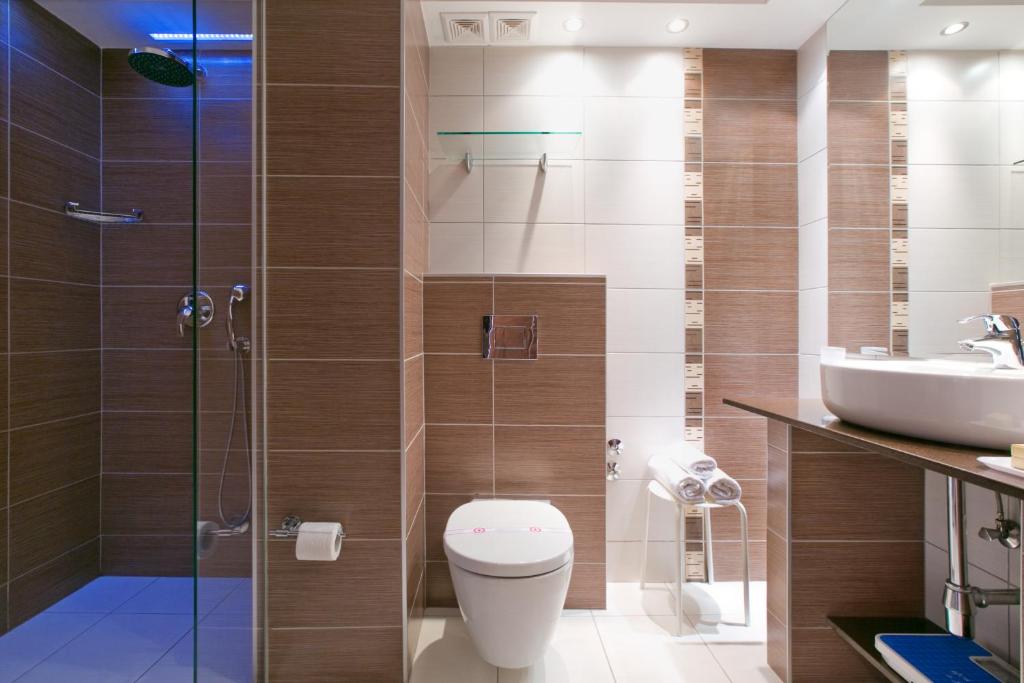 Mūsdienīgs vannas istabas interjers ar dušu un modernu sanitāro tehniku. Siltas krāsas flīzes un elegants dizains rada patīkamu un relaksējošu atmosfēru.