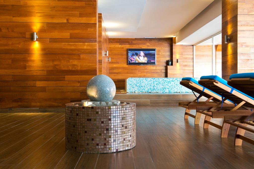 Mūsdienīgs spa interjers ar koka sienām, akmens fontālu un atpūtas krēslēm, radot relaksējošu atmosfēru. 