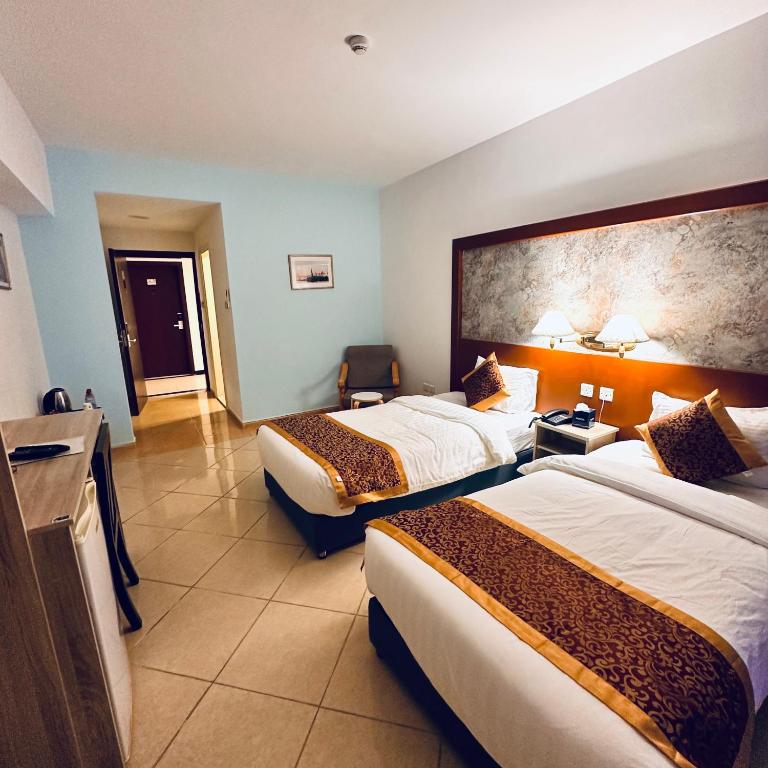 Mūsdienīga viesnīcas numuriņa interjers ar divām gultām, ērtu krēslu un galdu. Gaismas apstākļi rada siltu un viesmīlīgu atmosfēru.