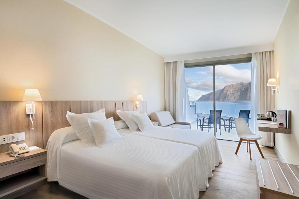 Mūsdienīgs viesnīcas numurs ar divām gultām, kas piedāvā skatu uz jūru un kalniem. Interjers ir gaišs un elegants, ar ērtībām, piemēram, telefons un tējkanna.