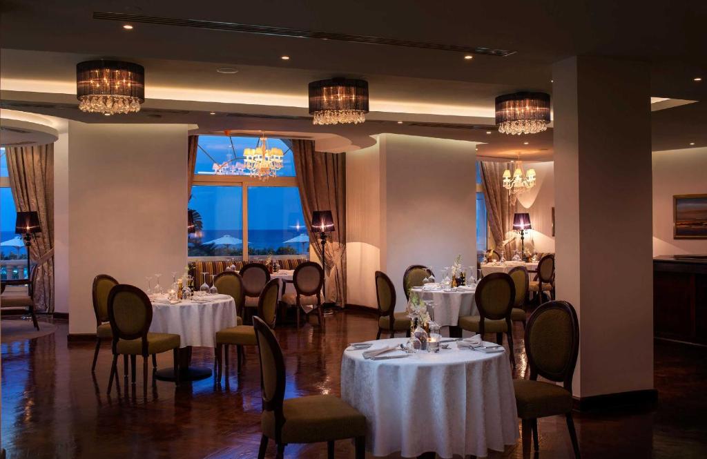 Elegantā restorāna interjers ar gaismu un izsmalcinātām galda klāšanām, kas rada romantisku atmosfēru. Logi piedāvā skatu uz jūru un nakts debesīm.