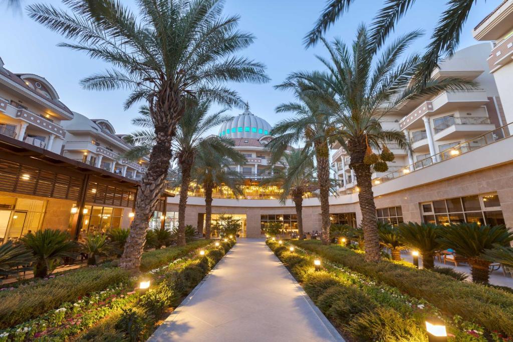 Mūsdienīgs kūrorts ar palmām un apgaismotu celiņu, kas ved uz elegantu ēku ar kupolu. Ideāla vieta relaksācijai un atpūtai.