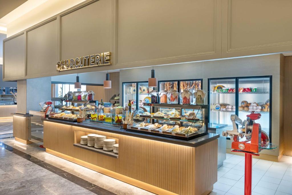 Mūsdienīgs charcuterie stends ar dažādiem gaļas un maizes produktiem, kas izkārtoti glītās vitrīnās, papildināts ar elegantu apgaismojumu.