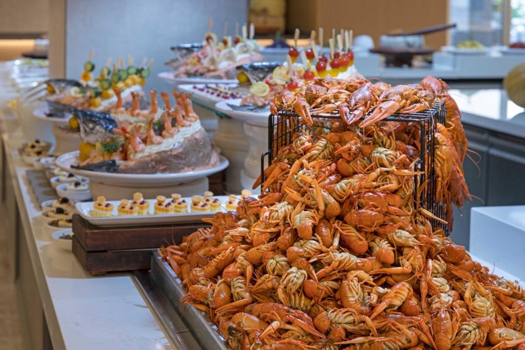Lielu garnu un jūras velšu bufete ar dažādiem ēdieniem, tostarp garnelēm un kūpinātiem zivīm, izkārtota elegantā restorānā.