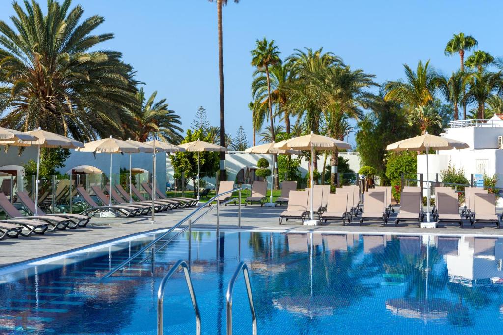 Vasaras atpūtas zonas ar baseinu, saules krēslām un palmām, kas rada relaksējošu atmosfēru. Ideāla vieta atpūtai un izklaidei.