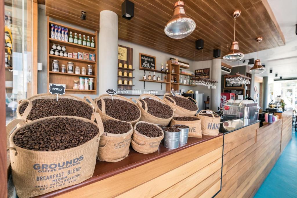 Kafijas bārs ar daudziem maisiem, kuros ir grauzdēti kafijas pupiņas, un stilīgu interjeru. Uz letes redzami dažādi kafijas maisījumi un dekorācijas.
