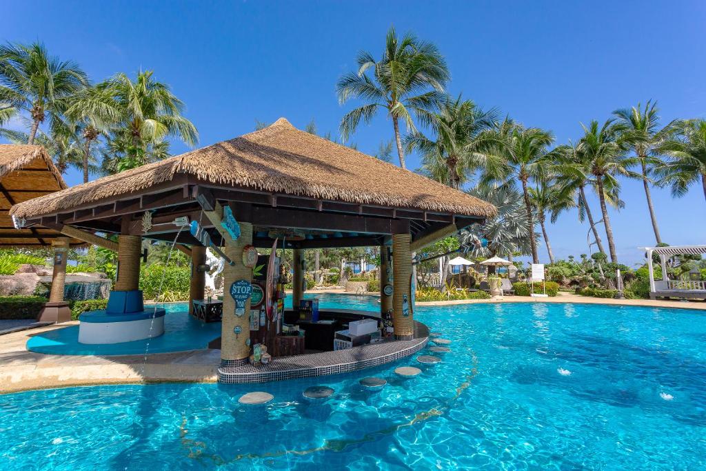 Eksotiska peldbaseina zona ar saliekamu jumtu un palmām, kas ieskauj ūdeni. Ideāla vieta atpūtai un relaksācijai.