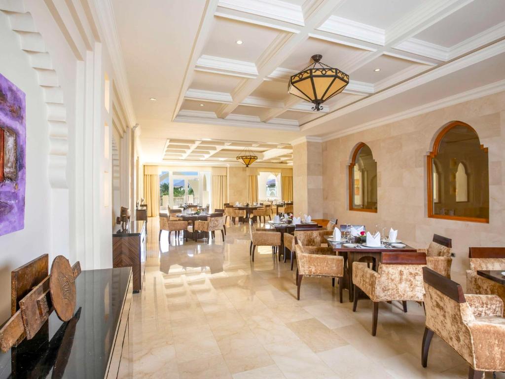 Elegants restorāns ar mīkstām krēslām un stilīgu interjeru, kurā ir skats uz dārzu. Gaismas apgaismojums un modernā arhitektūra rada viesmīlīgu atmosfēru.