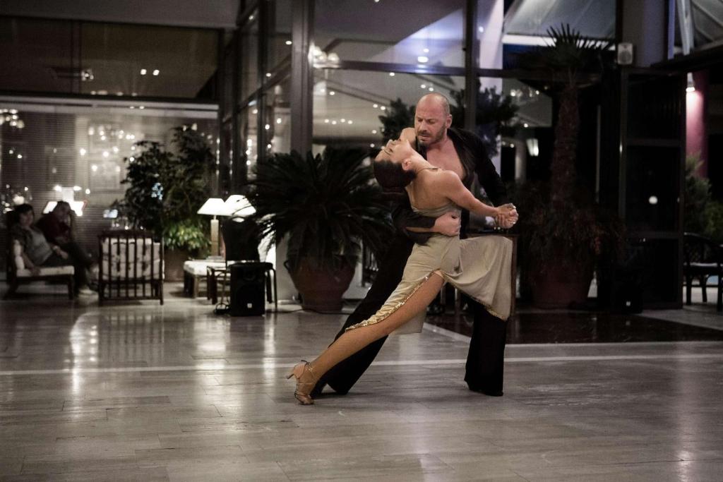 Pāris dejā elegantā vidē, ar mīkstu apgaismojumu un zaļām augu kompozīcijām. Deja izstaro kaislību un harmoniju.