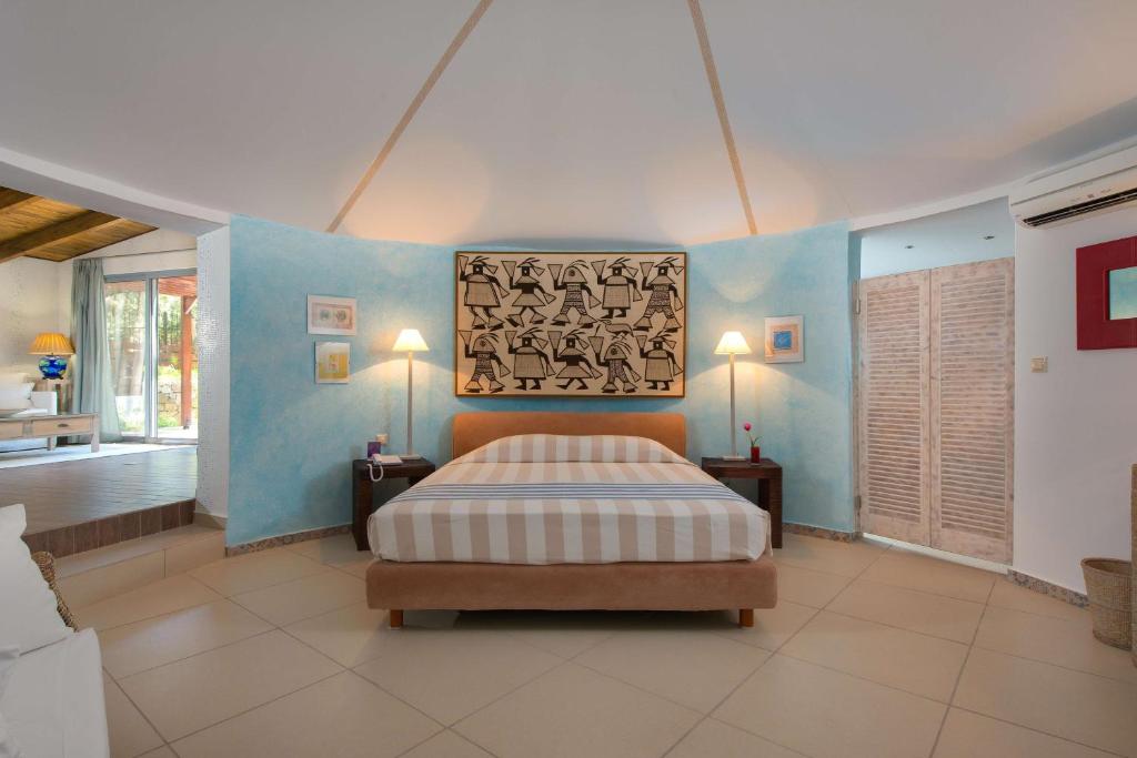 Mūsdienīgs guļamistabas interjers ar gultu un mākslas darbu uz sienas, kas papildina telpas estētiku. Gaismas un krāsainu akcentu kombinācija rada relaksējošu atmosfēru.