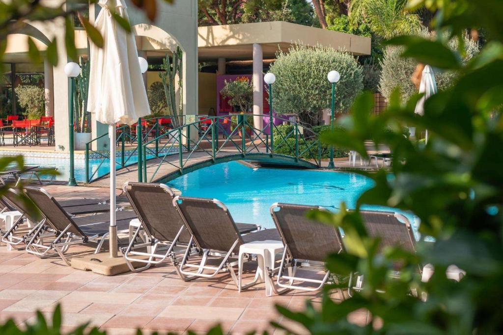 Baseins ar sauļošanās krēsliem un saulessargiem, ieskauts zaļumiem un modernām ēkām. Ideāla vieta atpūtai un relaksācijai.