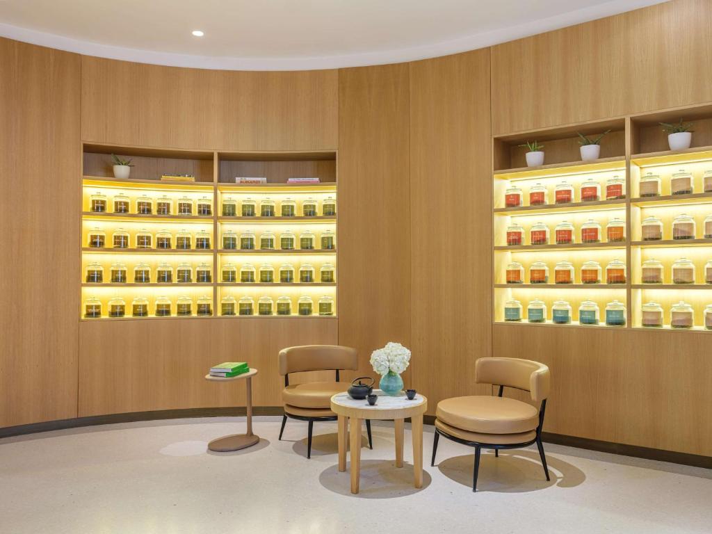 Mūsdienīga telpa ar koka akcentiem, kurās redzamas glabāšanas vitrīnas ar dažādu krāsu burkām un ērta sēdvieta. Ideāla atmosfēra relaksācijai un tējas vai garšvielu izvēlei.