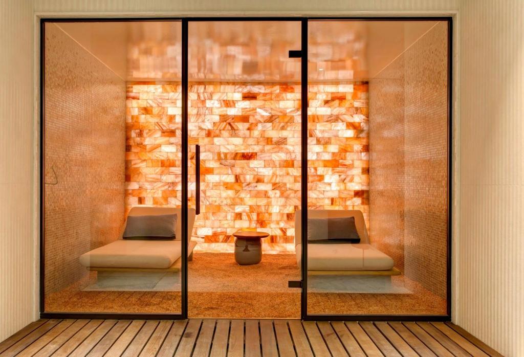 Sāls istaba ar mīkstiem dīvāniem un siltu apgaismojumu, radot relaksējošu atmosfēru. Stikla durvis nodrošina skatu uz siltajām, oranžām sāls plāksnēm.