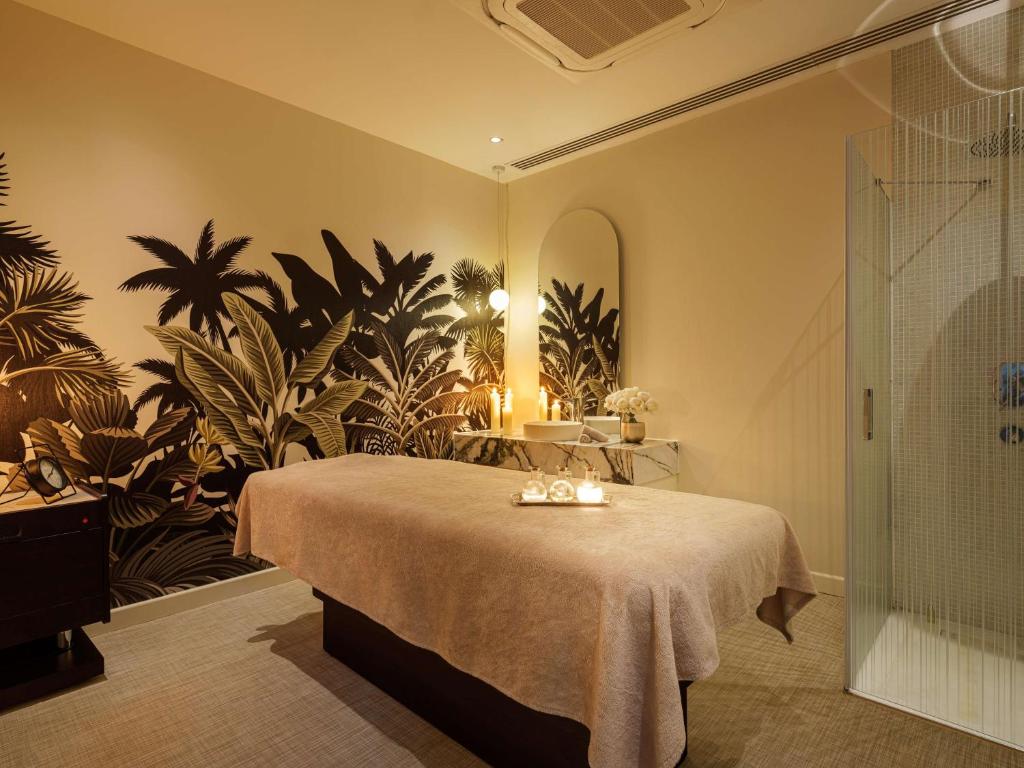 Mūsdienīgs SPA telpa ar eksotisku augu sienu apdari, masāžas galdu un relaksējošu atmosfēru, kas iedvesmo mieru un atpūtu.