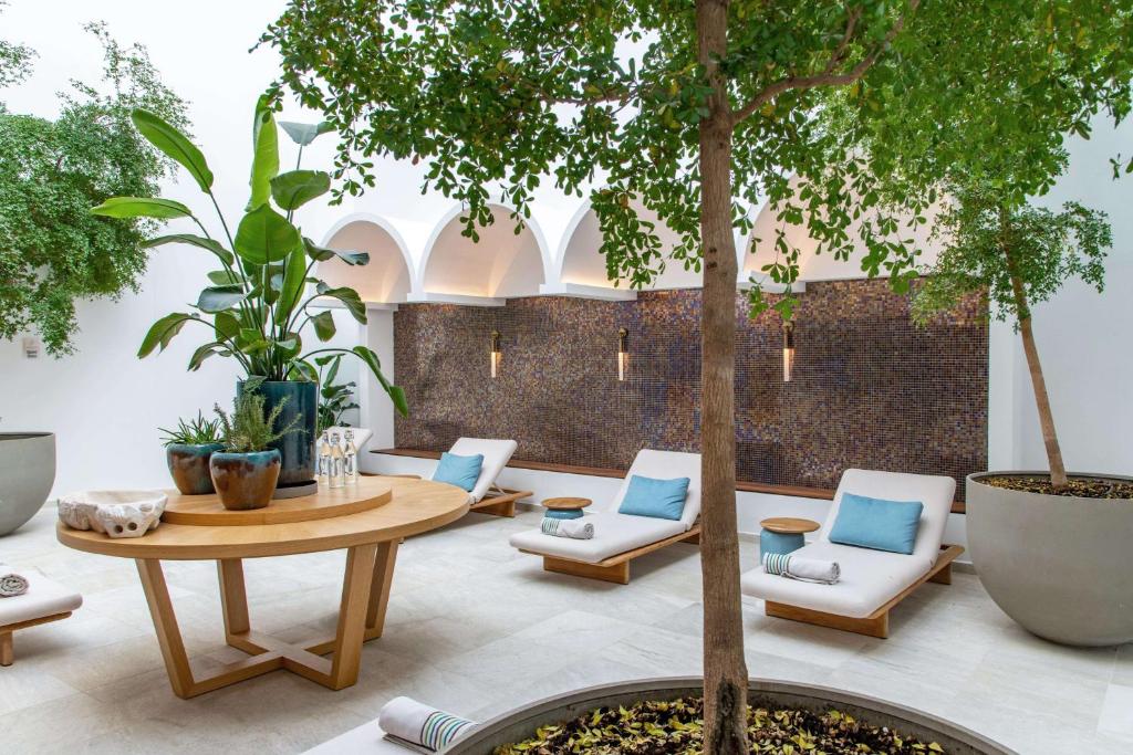 Mūsdienīgs un relaksējošs spa interjers ar ērtām guļvietām, zaļām augiem un elegantu koka galdu, radot mierīgu atmosfēru.