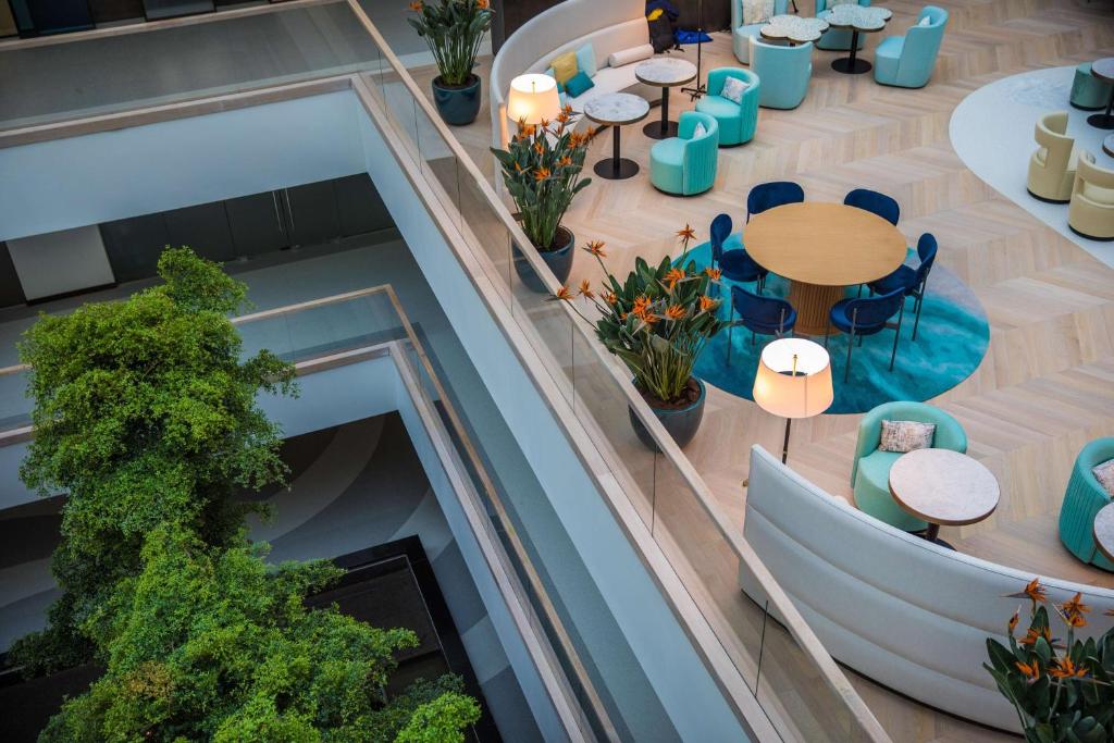 Mūsdienīga interjera ainava ar stilu, kurā redzami eleganti mēbeļu komplekti, ziedi un dzīvā auga elementiem. Telpa ir veidota ar gaišām krāsām un mūsdienīgu dizainu, radot patīkamu atmosfēru.