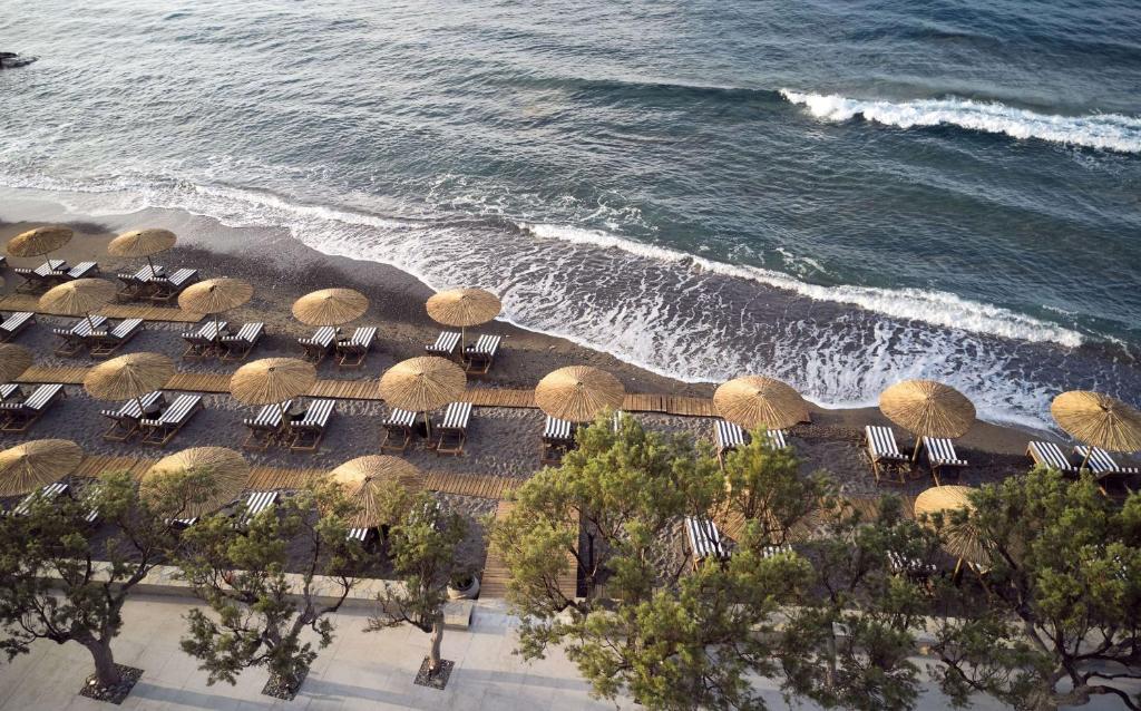 Pludmales skats ar saulessargiem un guļamkrēsliem gar viļņotām jūrmalām, veidojot mierīgu un relaksējošu atmosfēru.