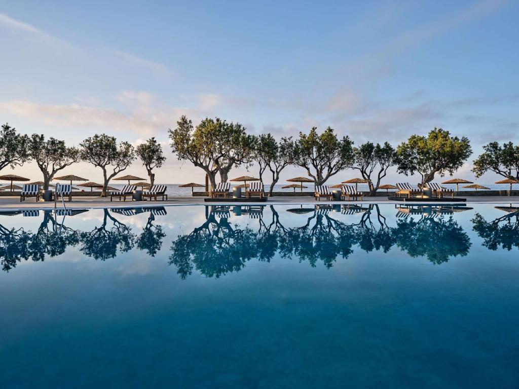 Baseins ar atspīdumiem, ko ieskauj koki un sauļošanās krēsli, radot mierīgu atmosfēru. Ideāla vieta relaksācijai pie jūras.