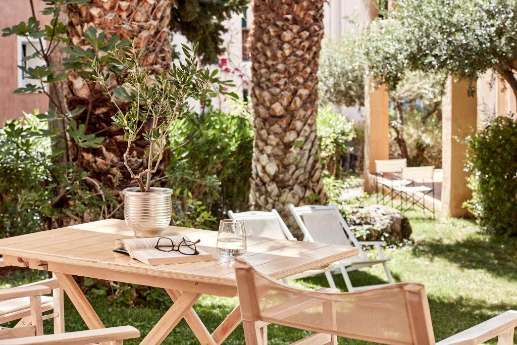 Koka galds ar puķu podu un grāmatu dārzā, apkārt palmām un zaļajām augu lapām, radot mierīgu un relaksējošu atmosfēru.