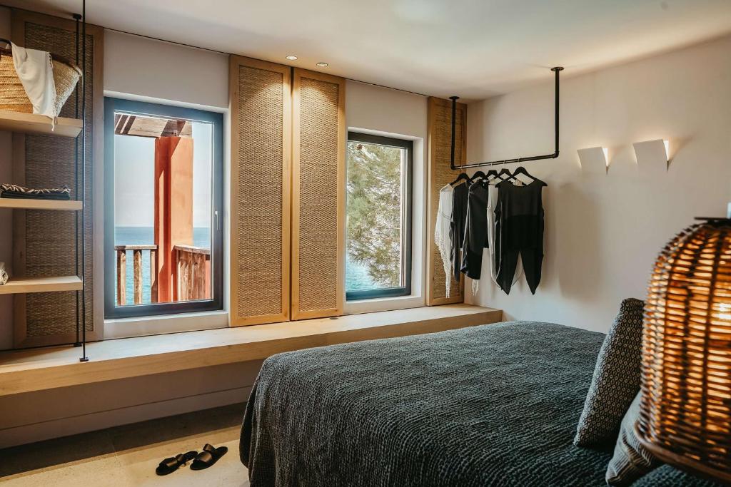 Mūsdienīgs guļamistabas interjers ar skatu uz jūru, kas iekārtots ar dabīgiem materiāliem un stilīgu apgaismojumu. Logi ļauj ieplūst dabiskai gaismai un piedāvā relaksējošu atmosfēru.