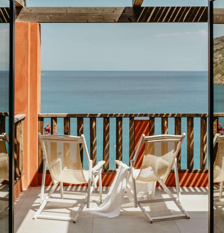 Divas atpūtas krēslus terasē ar skatu uz jūru, apgaismojot sauli un mierīgu atmosfēru. Ideāla vieta relaksācijai un dabiska skaistuma baudīšanai.